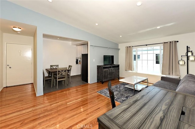 living room with light hardwood / wood-style floors and vaulted ceiling