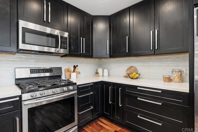 kitchen with hardwood / wood-style floors, appliances with stainless steel finishes, and tasteful backsplash