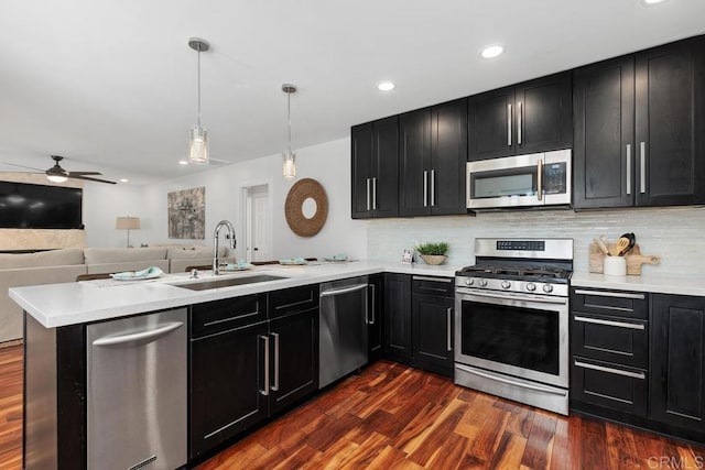 kitchen featuring appliances with stainless steel finishes, dark hardwood / wood-style flooring, sink, backsplash, and kitchen peninsula