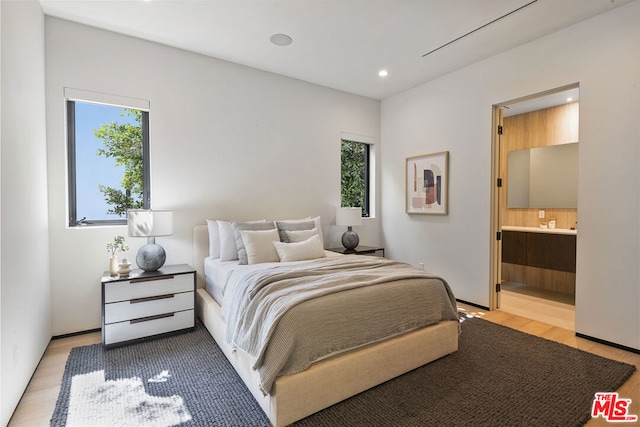 bedroom featuring light hardwood / wood-style floors, multiple windows, and ensuite bathroom