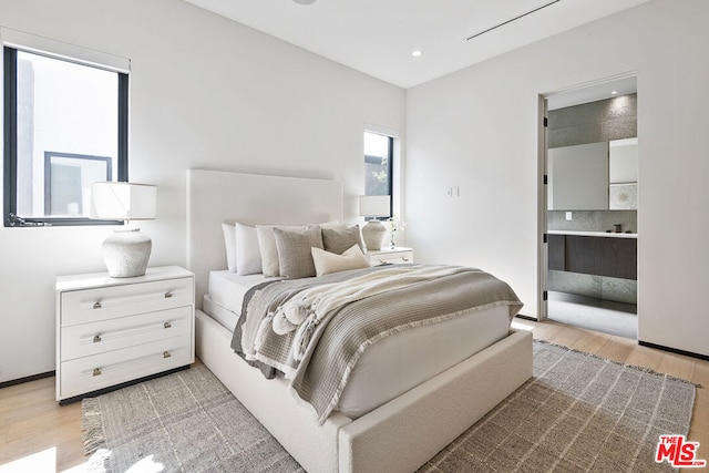 bedroom featuring light hardwood / wood-style flooring and ensuite bath