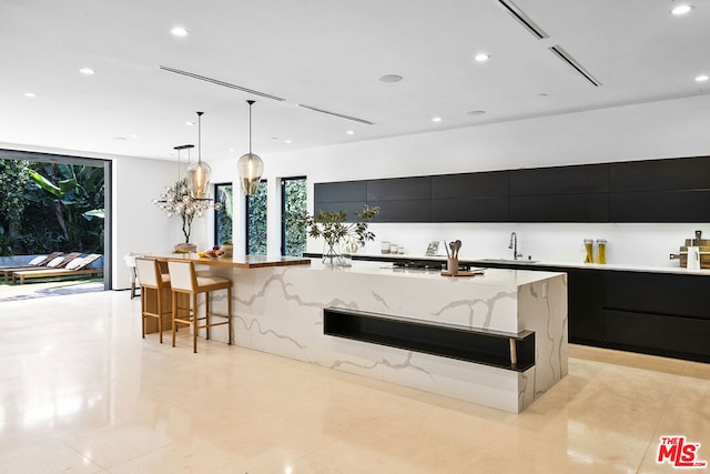 kitchen featuring a kitchen breakfast bar, a large island, sink, and pendant lighting