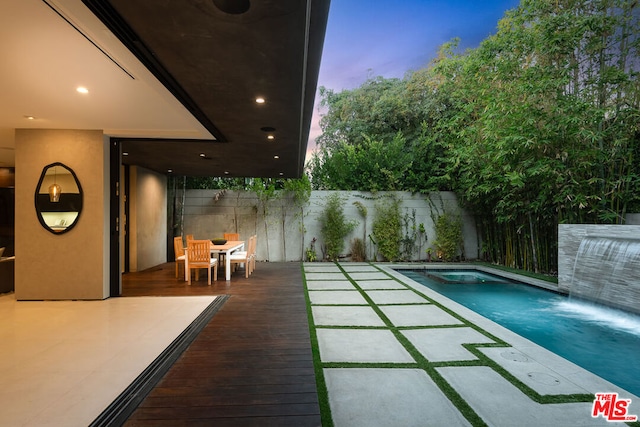 pool at dusk featuring a patio area