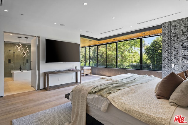 bedroom with ensuite bathroom, floor to ceiling windows, and light hardwood / wood-style flooring