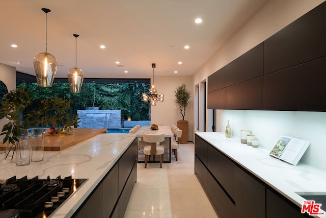 kitchen featuring black gas cooktop, pendant lighting, light stone counters, and a notable chandelier