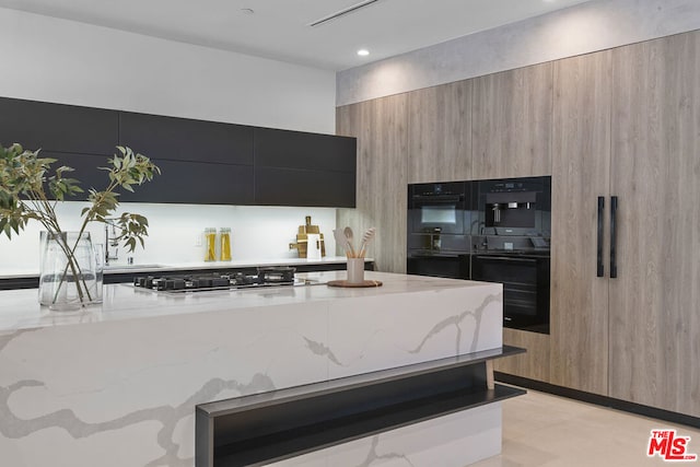 kitchen with double oven, light stone counters, and stainless steel gas cooktop