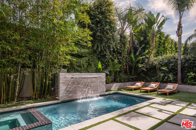 view of pool with an in ground hot tub, pool water feature, and a patio