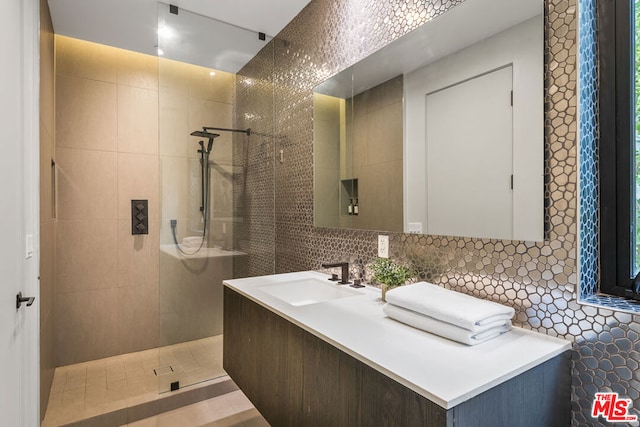 bathroom with vanity, a tile shower, tile walls, and tasteful backsplash