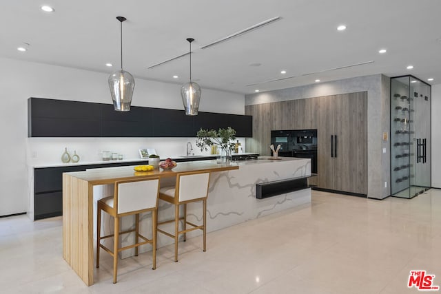 kitchen featuring pendant lighting, sink, a large island, and a breakfast bar area