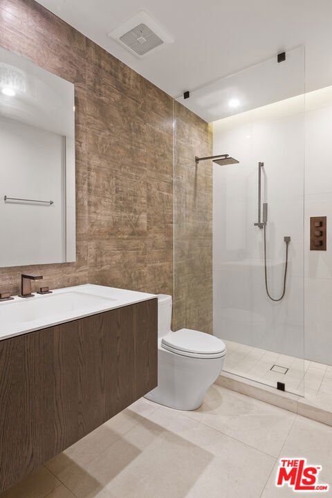 bathroom with tile patterned flooring, vanity, tile walls, and toilet