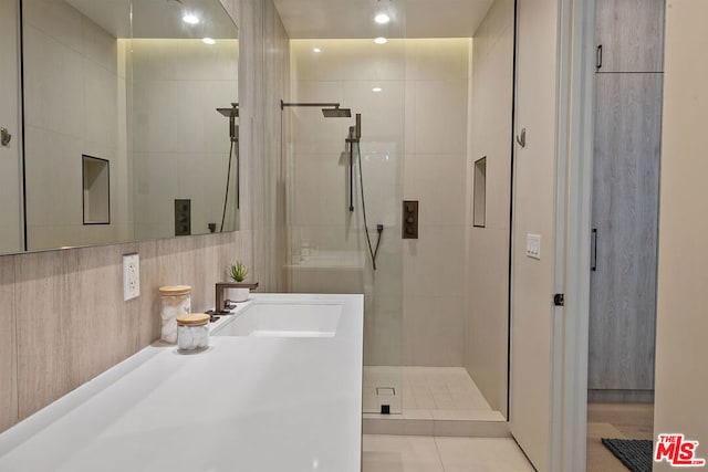 bathroom featuring tile patterned flooring, a shower with shower door, sink, and tile walls