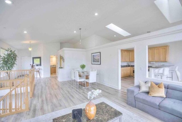 living room featuring vaulted ceiling with skylight and light hardwood / wood-style flooring