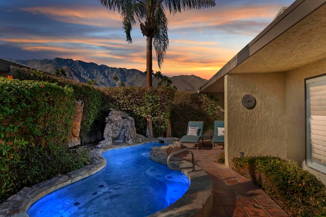 pool at dusk with a mountain view and a patio area