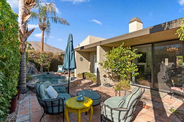 view of patio with outdoor lounge area, a mountain view, and pool water feature