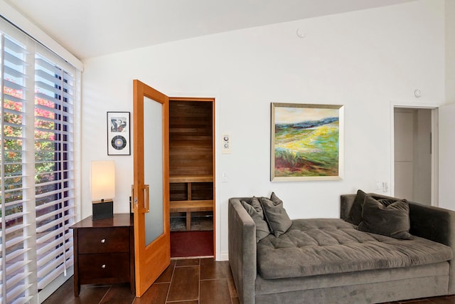 sitting room with dark tile patterned floors and lofted ceiling