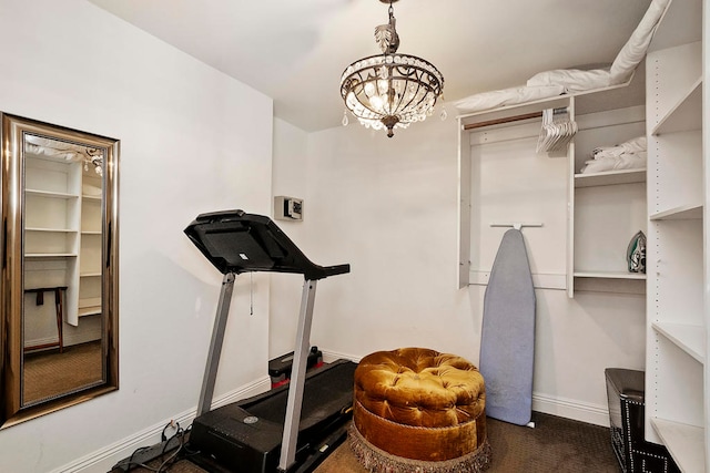 exercise room featuring dark carpet and a chandelier