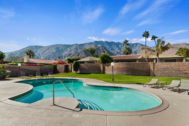 view of swimming pool with a lawn, a patio area, and a mountain view