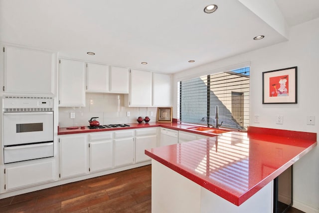 kitchen featuring kitchen peninsula, white cabinetry, dark wood-type flooring, and white appliances