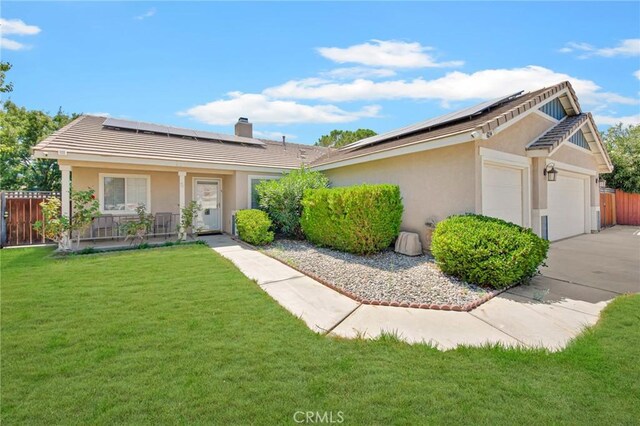 ranch-style home with a front yard, solar panels, a garage, and a porch