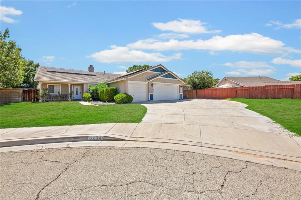 ranch-style home with solar panels, a garage, and a front lawn