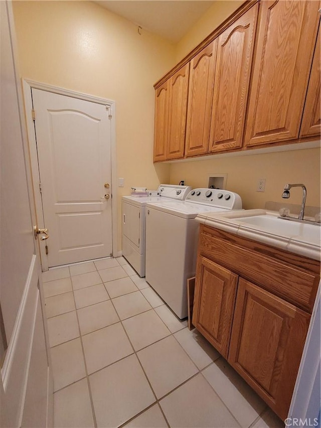 laundry room featuring cabinets, light tile patterned floors, sink, and washing machine and clothes dryer