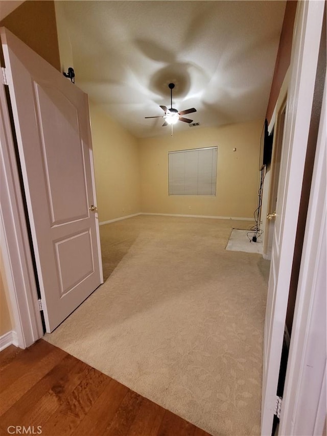 interior space with ceiling fan and light colored carpet