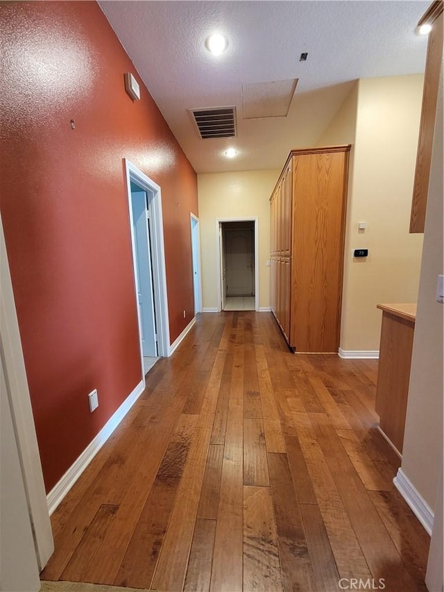 hallway featuring light hardwood / wood-style floors and a textured ceiling