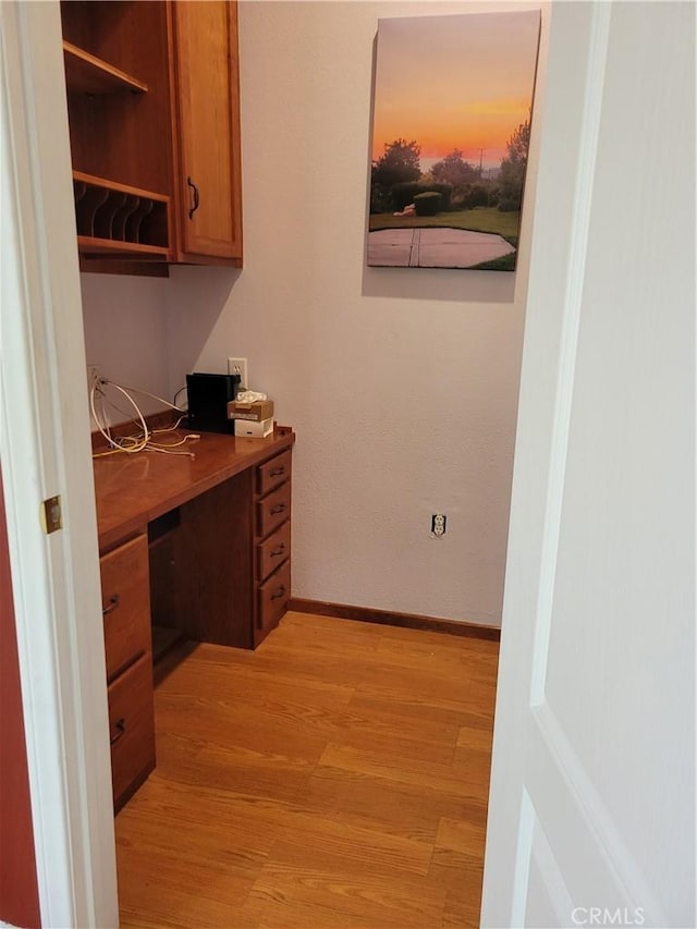 office area with light wood-type flooring and built in desk