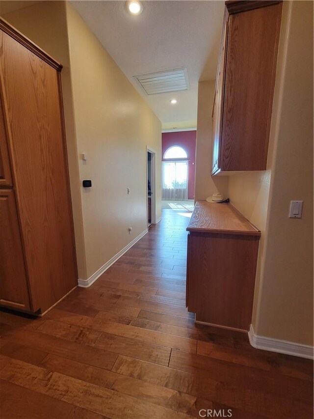 hallway featuring dark hardwood / wood-style floors and vaulted ceiling