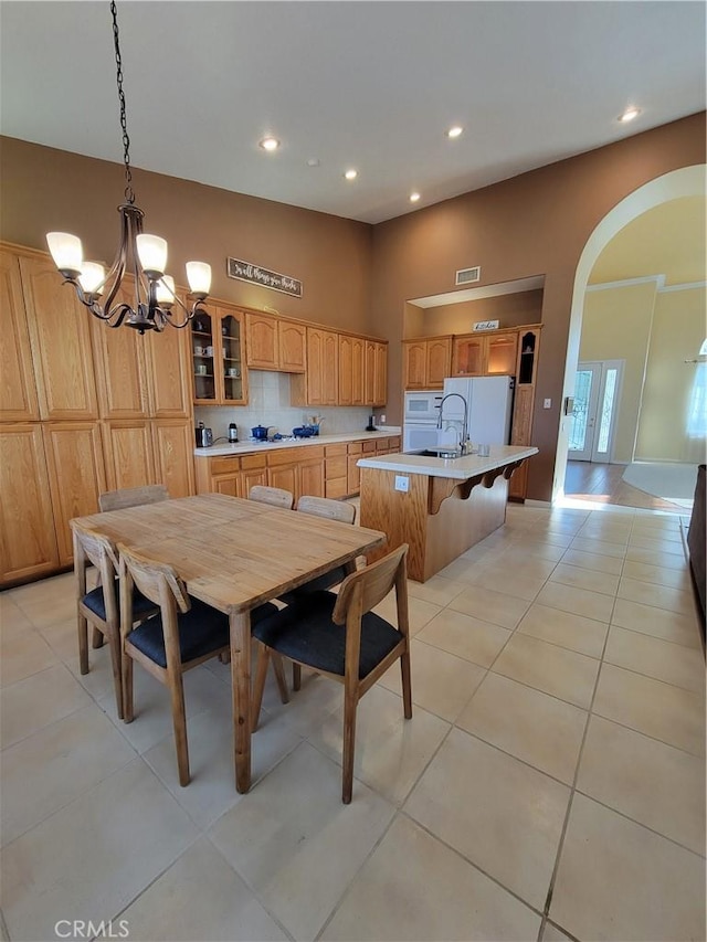 dining room with sink, light tile patterned floors, and a notable chandelier