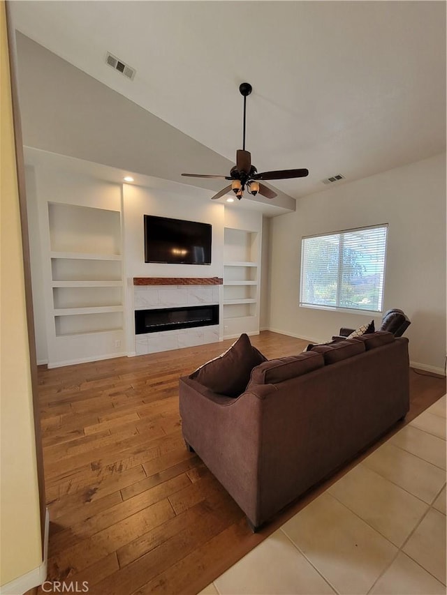 living room with hardwood / wood-style floors, vaulted ceiling, ceiling fan, and built in shelves