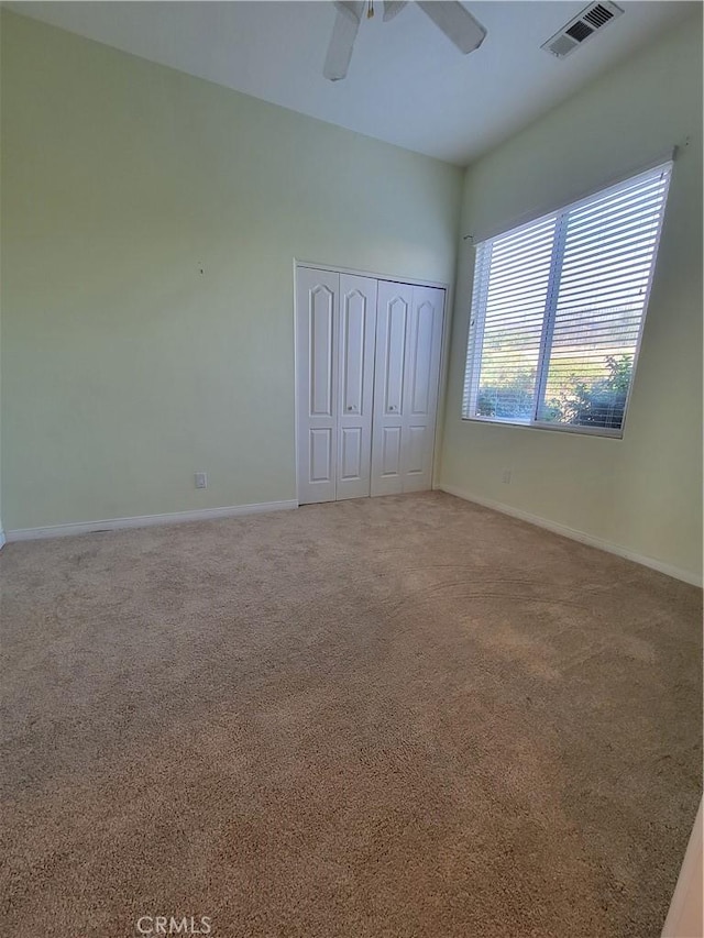 unfurnished bedroom featuring carpet floors, a closet, and ceiling fan