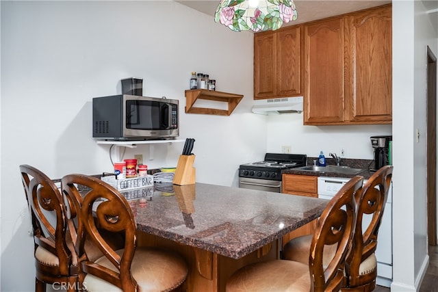 kitchen featuring a kitchen breakfast bar, dark stone countertops, sink, and appliances with stainless steel finishes