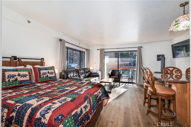 bedroom with access to outside, hardwood / wood-style flooring, and multiple windows