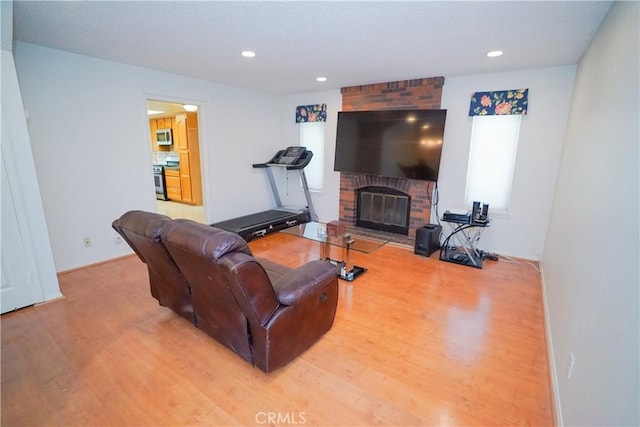 living room with light hardwood / wood-style floors and a brick fireplace