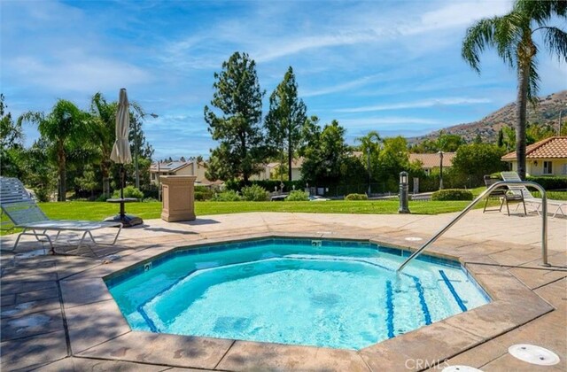 view of pool featuring an in ground hot tub, a mountain view, a patio area, and a lawn