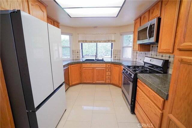 kitchen featuring appliances with stainless steel finishes, tasteful backsplash, light tile patterned floors, and sink