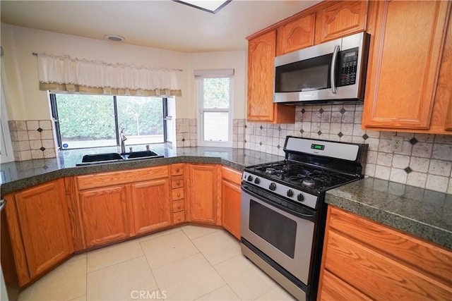 kitchen featuring decorative backsplash, light tile patterned floors, stainless steel appliances, and sink