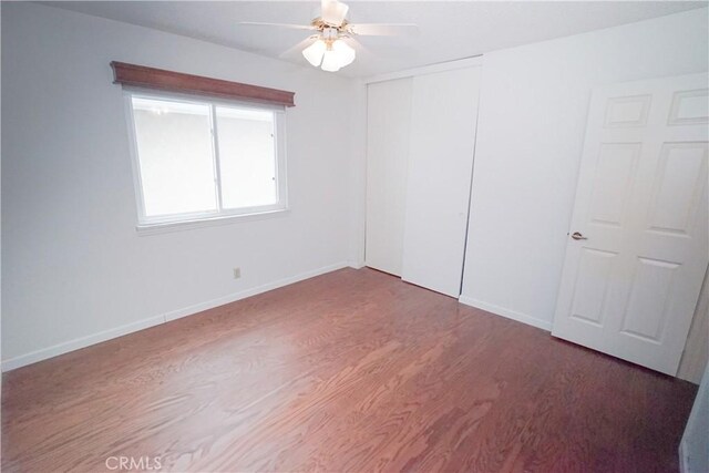 unfurnished bedroom with ceiling fan, a closet, and hardwood / wood-style flooring