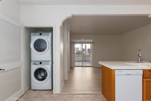 washroom with sink, stacked washer and dryer, and light hardwood / wood-style flooring