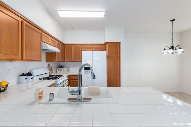 kitchen featuring pendant lighting, tile countertops, white appliances, an inviting chandelier, and sink