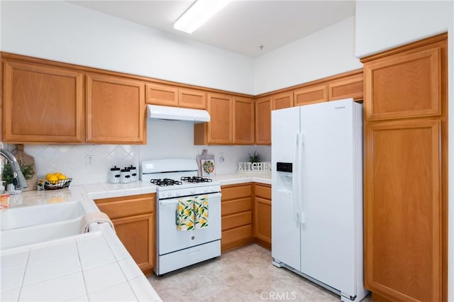 kitchen with white appliances, tasteful backsplash, tile counters, and sink