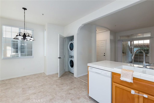 laundry room with stacked washer / drying machine, a notable chandelier, and sink