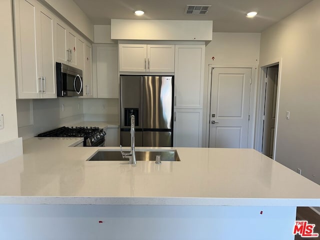 kitchen featuring kitchen peninsula, white cabinetry, sink, and appliances with stainless steel finishes