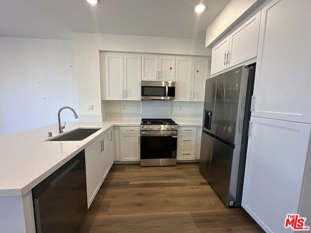 kitchen featuring white cabinetry, sink, stainless steel appliances, dark hardwood / wood-style flooring, and kitchen peninsula