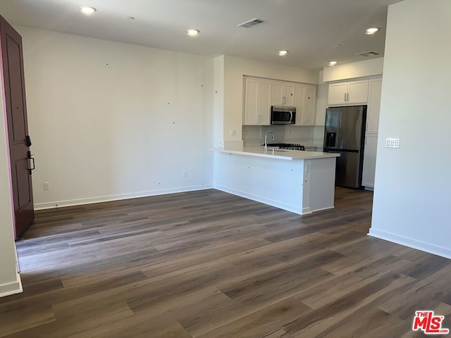 kitchen with white cabinetry, sink, dark hardwood / wood-style flooring, kitchen peninsula, and appliances with stainless steel finishes