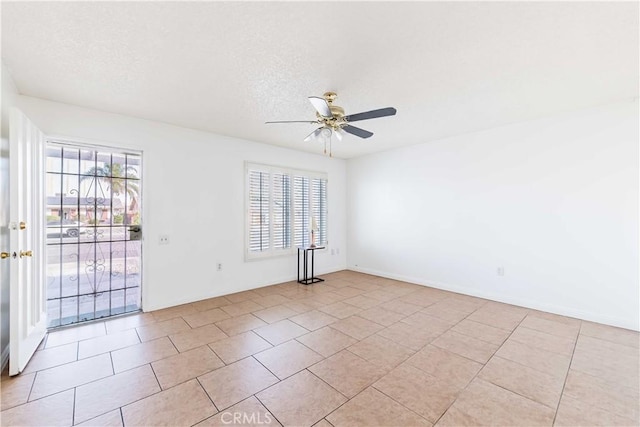 spare room with ceiling fan, plenty of natural light, light tile patterned flooring, and a textured ceiling