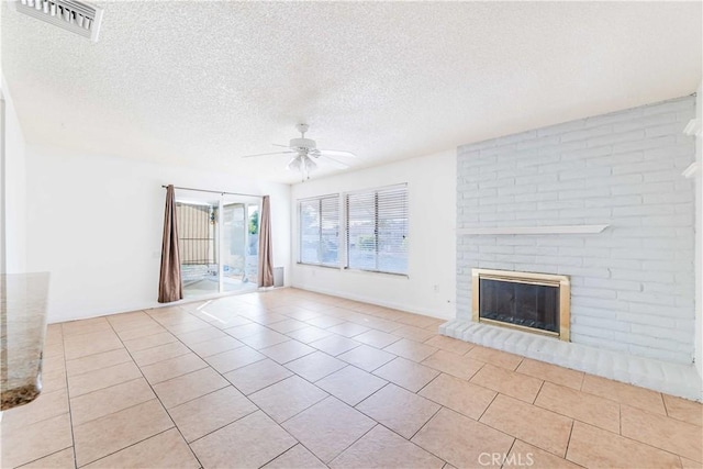 unfurnished living room featuring a brick fireplace, a textured ceiling, ceiling fan, and light tile patterned flooring