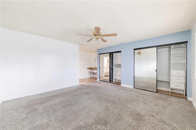 unfurnished bedroom featuring ceiling fan, multiple closets, a textured ceiling, and carpet flooring