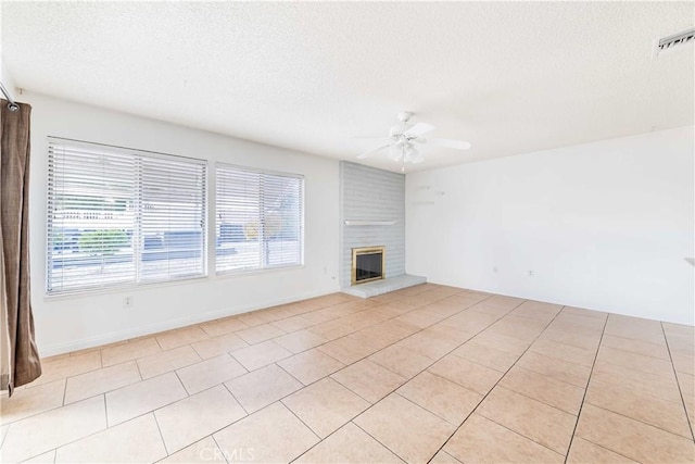 unfurnished living room with ceiling fan, light tile patterned flooring, a textured ceiling, and a fireplace